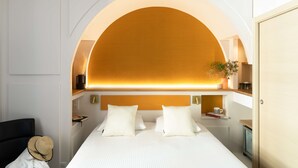 A hotel room with a large bed, a headboard with a warm light, a small table with a plant, and a nightstand with a lamp. - Best Western Hotel Du Roy D'aragon (Bonifacio)