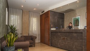 A modern hotel reception area with a reception desk, a sofa, a potted plant, and a framed picture on the wall. - Hotel Zara Milano (Milan)