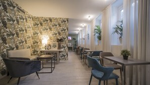 A modern dining area with a floral wallpaper, a sofa, and several chairs. - Hotel Zara Milano (Milan)