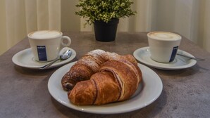 A table with two cups of coffee, a plate with a croissant, and a potted plant. - Hotel Zara Milano (Milan)