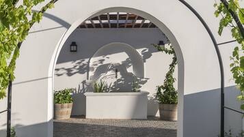 An arched architectural feature with a decorative element, potted plants, and a lantern.