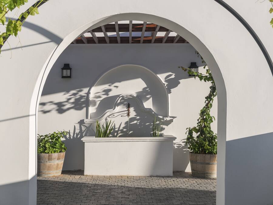 An arched architectural feature with a decorative element, potted plants, and a lantern.