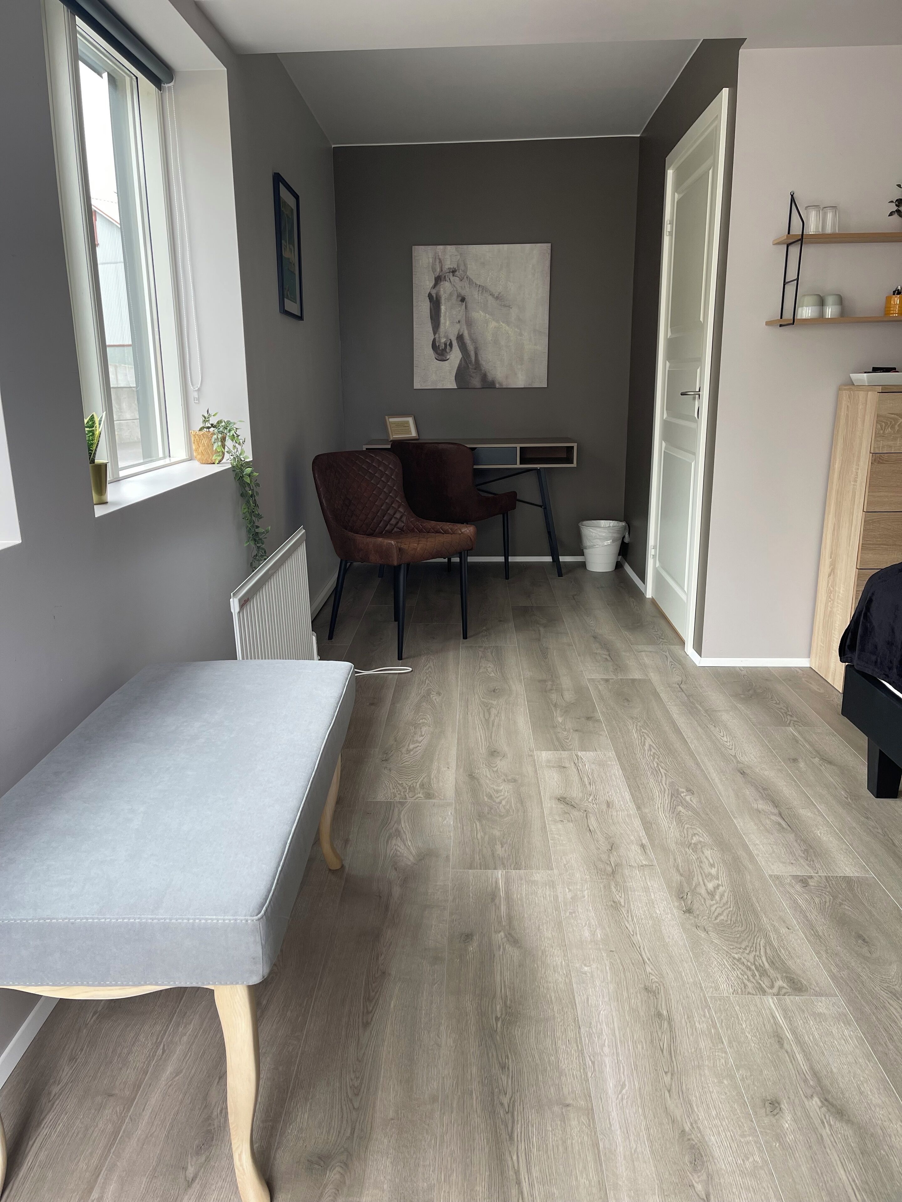 Una sala de estar moderna con un sofá gris, un sillón marrón, una mesa de comedor y un ventanal grande.