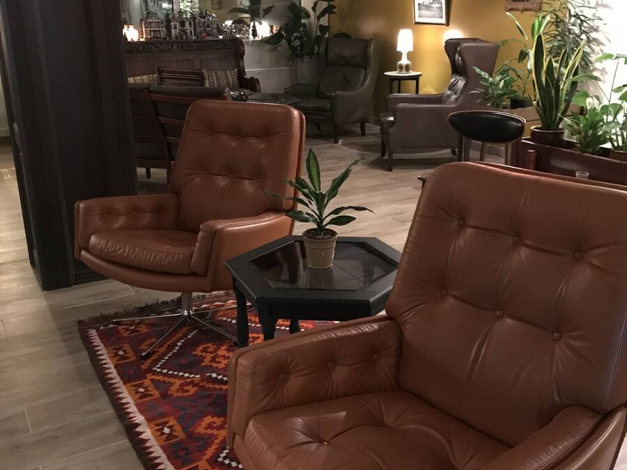A modern living room with leather armchairs, a glass coffee table, and a patterned rug.
