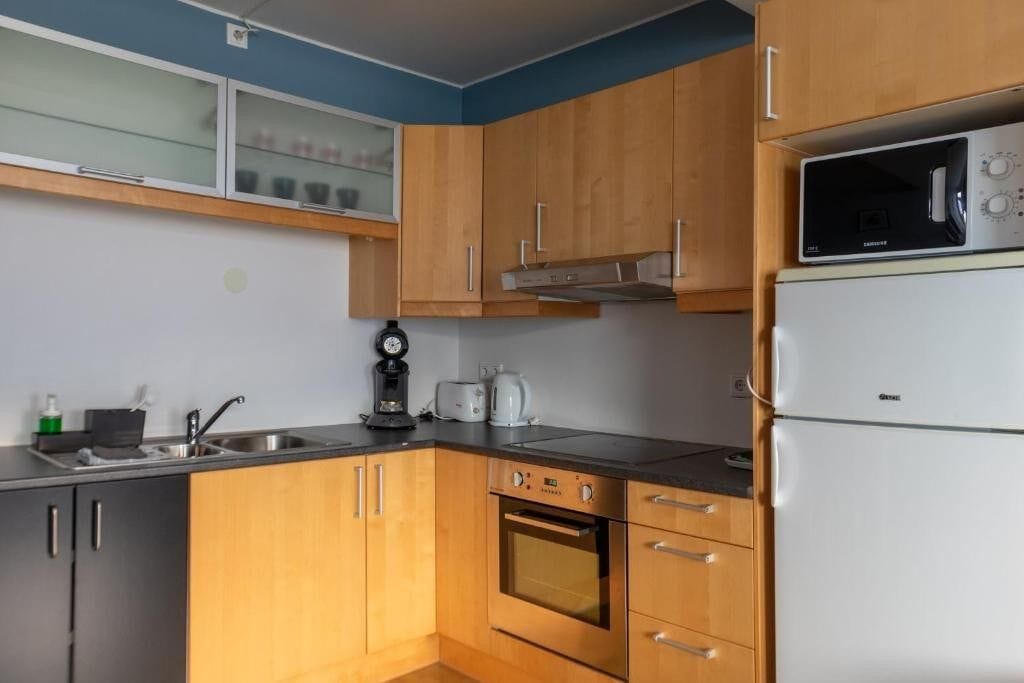 Una cocina compacta con armarios de madera, horno empotrado, microondas y cafetera.