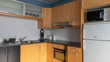 Una cocina compacta con armarios de madera, horno empotrado, microondas y cafetera.