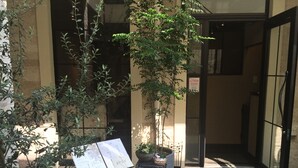 An outdoor entrance with a stone floor, potted plants, a menu board, and a door with a sign. - Business Hotel SUNP (Shizuoka)