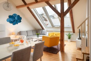 A modern loft apartment with a dining area, a sofa, and a yellow armchair. - Residence Vocelova (Prague)
