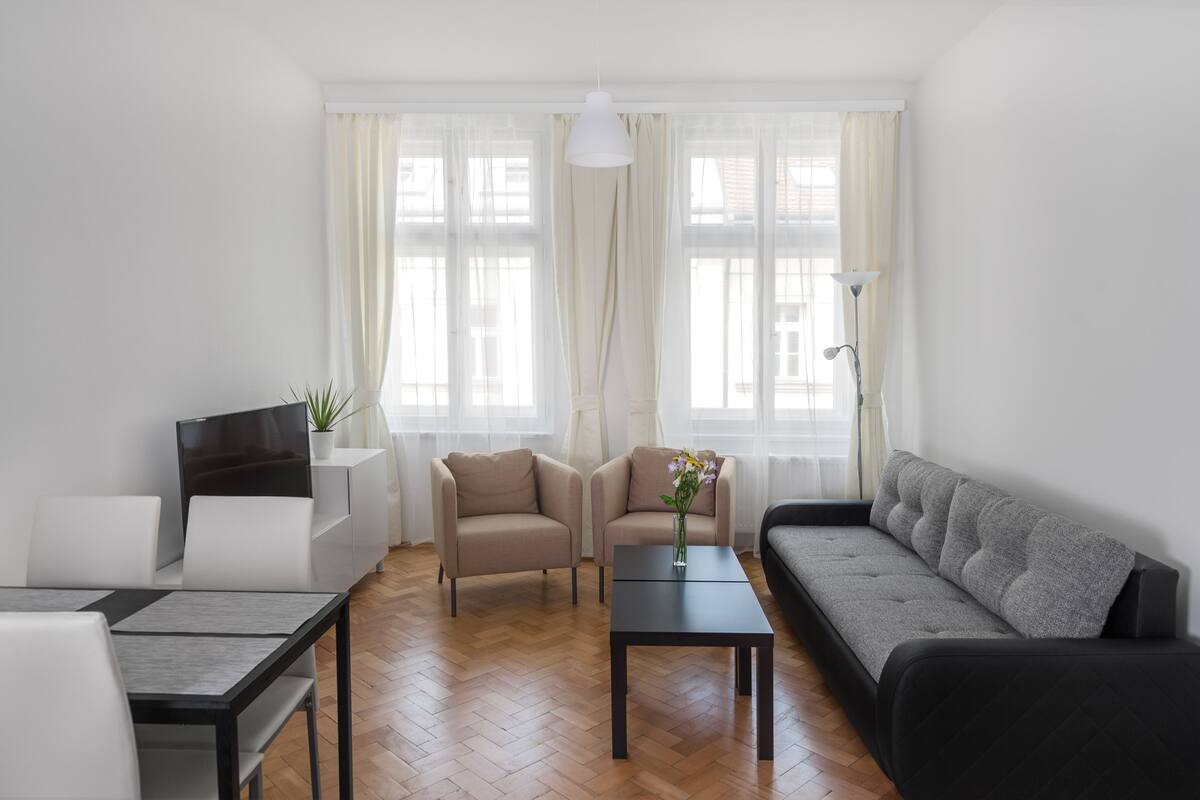A modern living room with a sofa, two armchairs, a coffee table, and a TV on a stand.