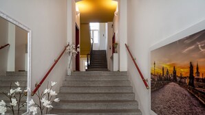 En trappa med en spegel på vänster sida och en målning av en stadsbild på höger sida.