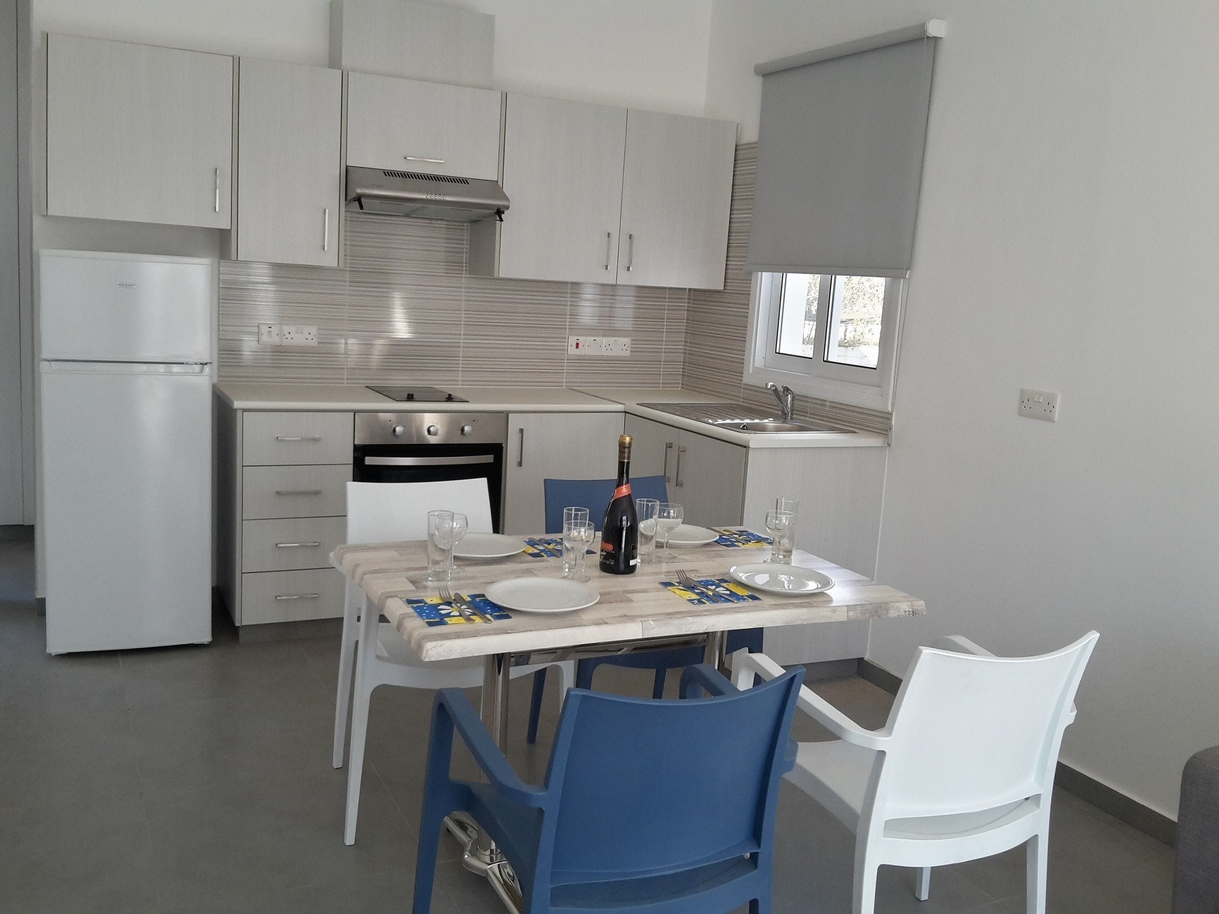 A modern kitchen with white cabinets, a built-in oven, and a window above the sink.