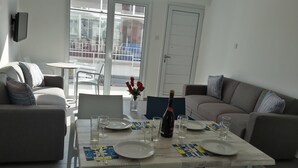 Un coin repas avec une table dressée pour quatre personnes, une bouteille de vin et un vase rempli de roses rouges.