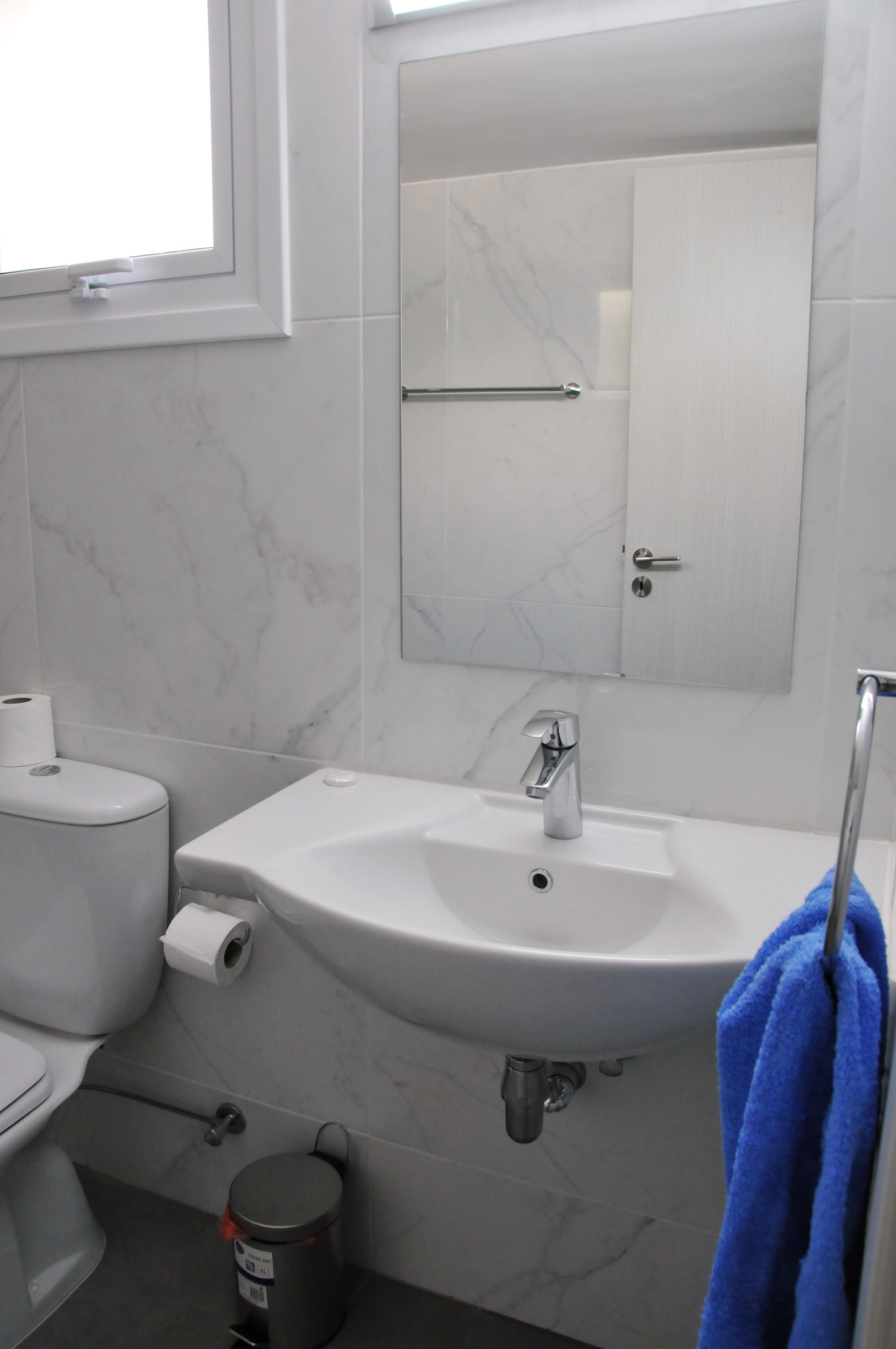 A bathroom with a toilet, sink, and mirror.