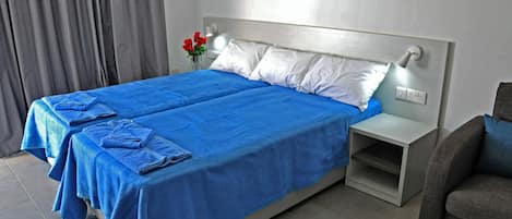A hotel room with a large bed, two pillows, a nightstand, and a vase with flowers.