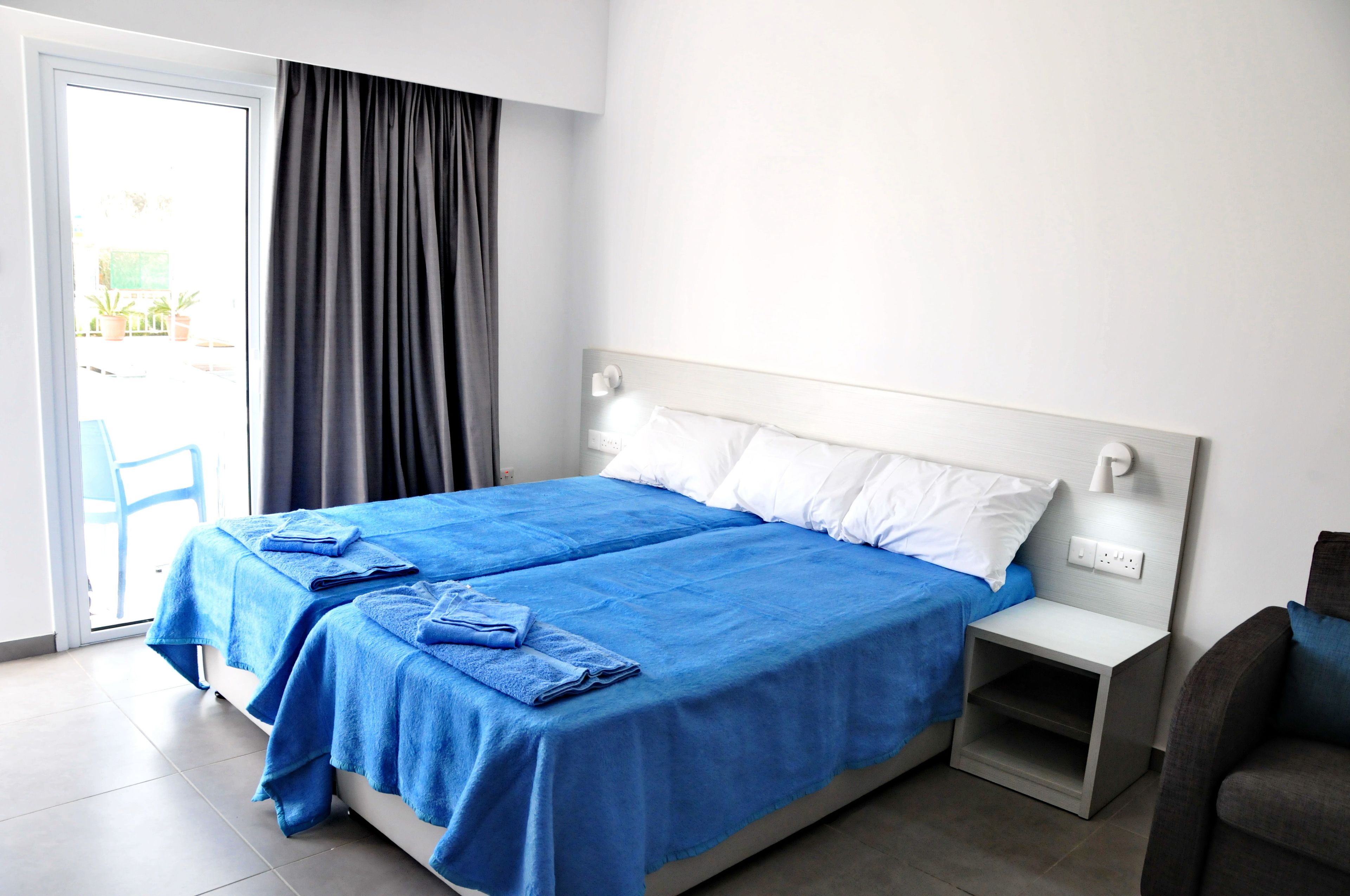Une chambre d’hôtel avec un lit, une table de chevet, une chaise et une vue sur l’extérieur.