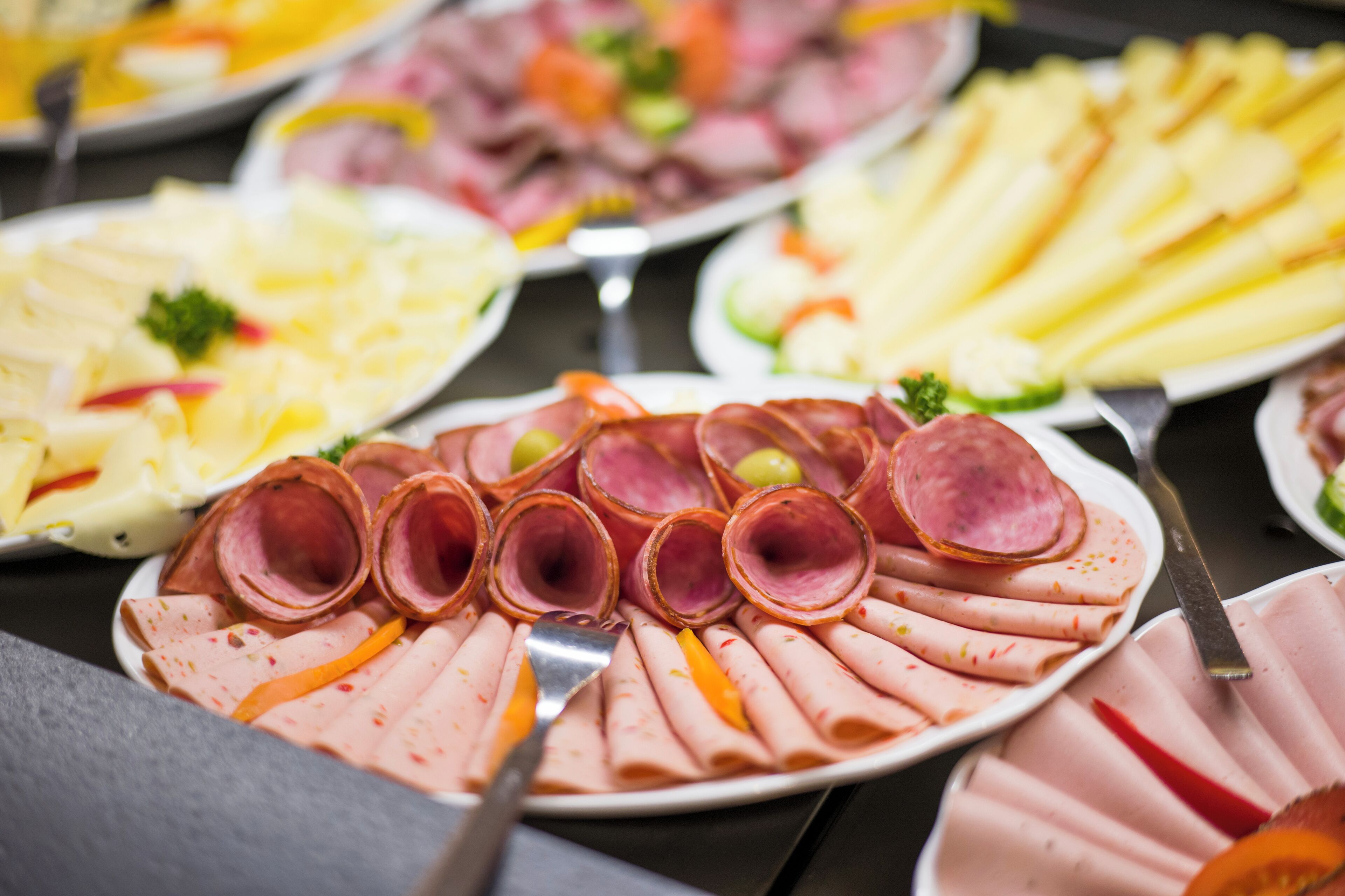 Un buffet proposant une variété de plats, notamment des viandes et des légumes coupés en tranches.