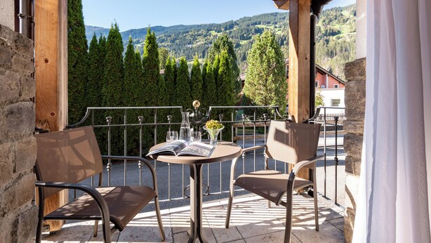 Een houten pergola met een tafel en stoelen, met uitzicht op een bergachtig landschap.