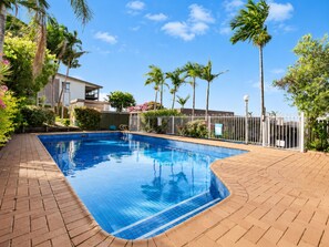 A rectangular swimming pool with a tiled edge, surrounded by a brick patio and a metal fence. - Gladstone CBD Motel (Gladstone)
