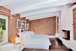 Une chambre à coucher comprenant un lit, une table de chevet, une fenêtre et un mur orné d’œuvres d’art abstraites.