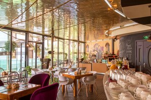 A restaurant with a high ceiling, large windows, and a bar area. - Cron Palace Tbilisi Hotel (Tbilisi)
