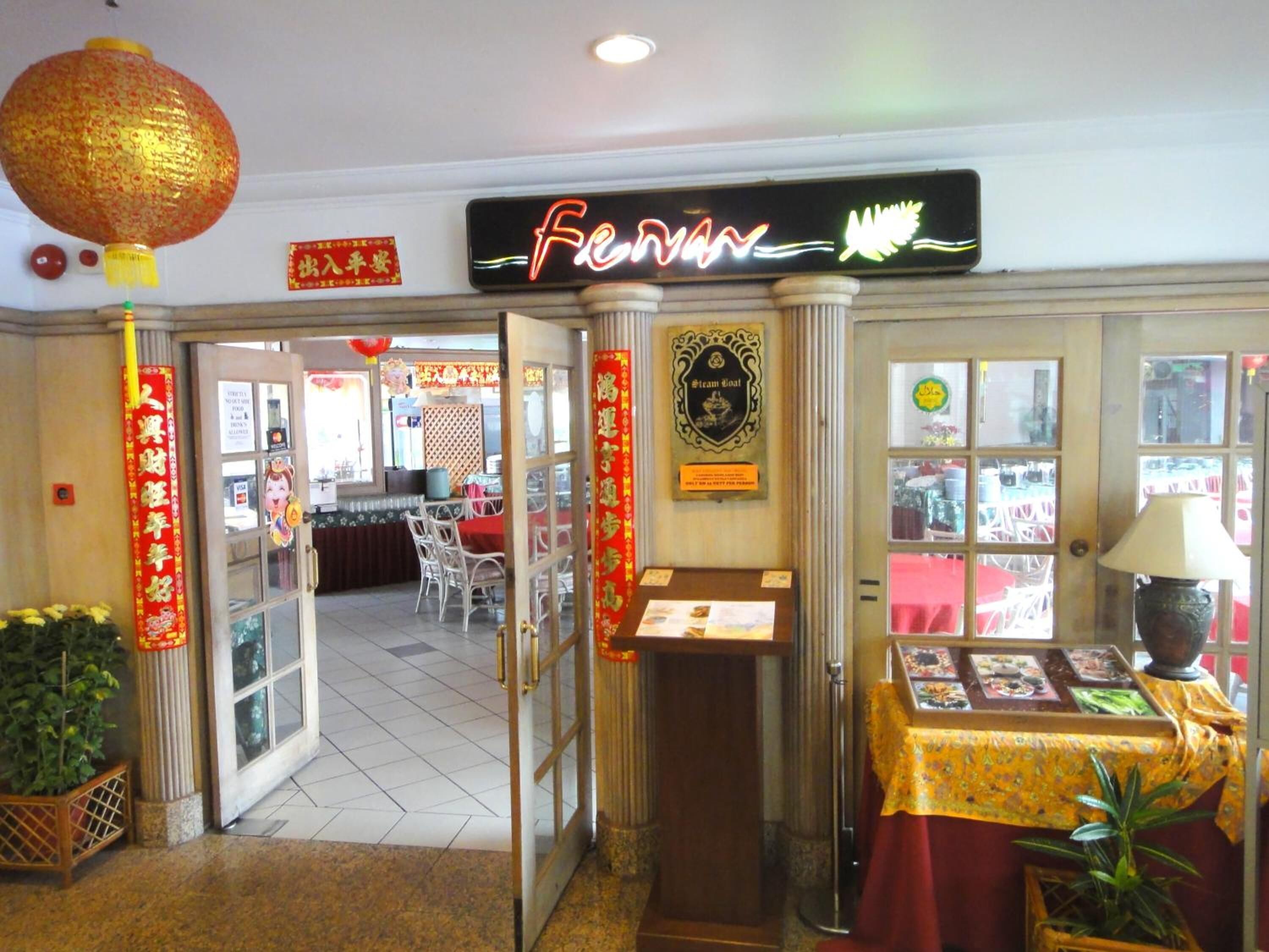A restaurant entrance with a neon sign, traditional decorations, and a display table.