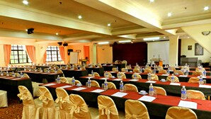 Un salón de conferencias con varias mesas, sillas y un escenario.