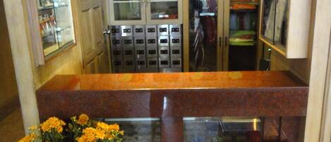 A souvenir corner with a sign, a display case with flowers, and a stainless steel trash bin.
