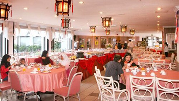 Comedor con mesas redondas cubiertas con manteles rojos, sillas blancas y faroles tradicionales colgando del techo.