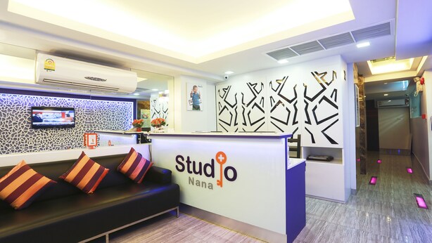 A reception area with a sofa, a TV, and a reception desk labeled 'Studio Nana'. - Studio Nana (Bangkok)