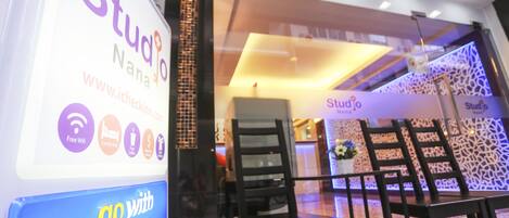 Un letrero de Studio Nanna con el logotipo 'go with VISA', puerta de vidrio de acceso y un interior moderno con sillas y mesas.