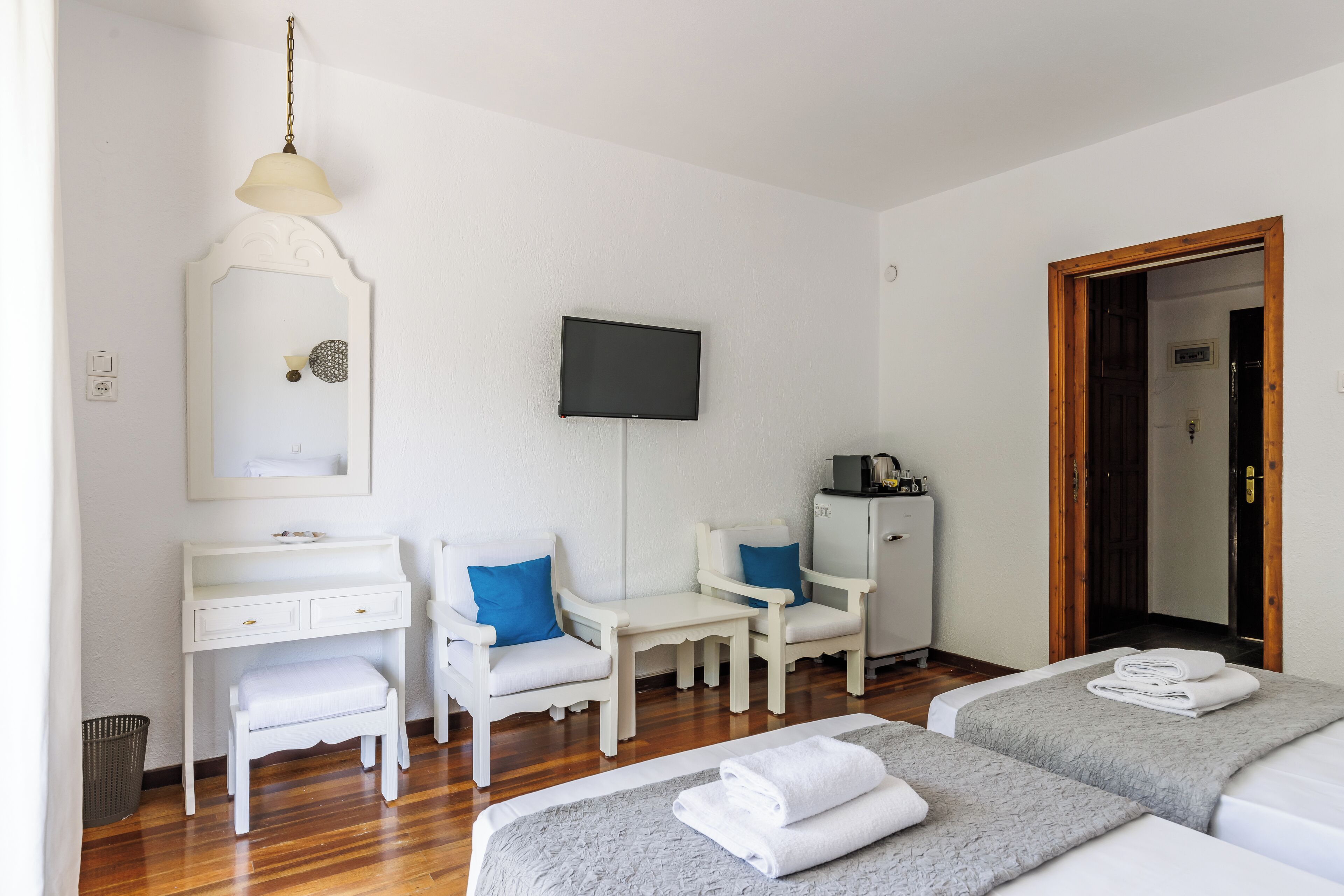 A hotel room with two beds, a desk, a chair, a TV, and a mirror.