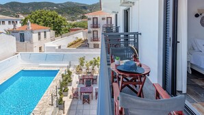 A balcony with a pool, outdoor furniture, and a view of the surrounding buildings and landscape. - Hotel Amalia (Skopelos)