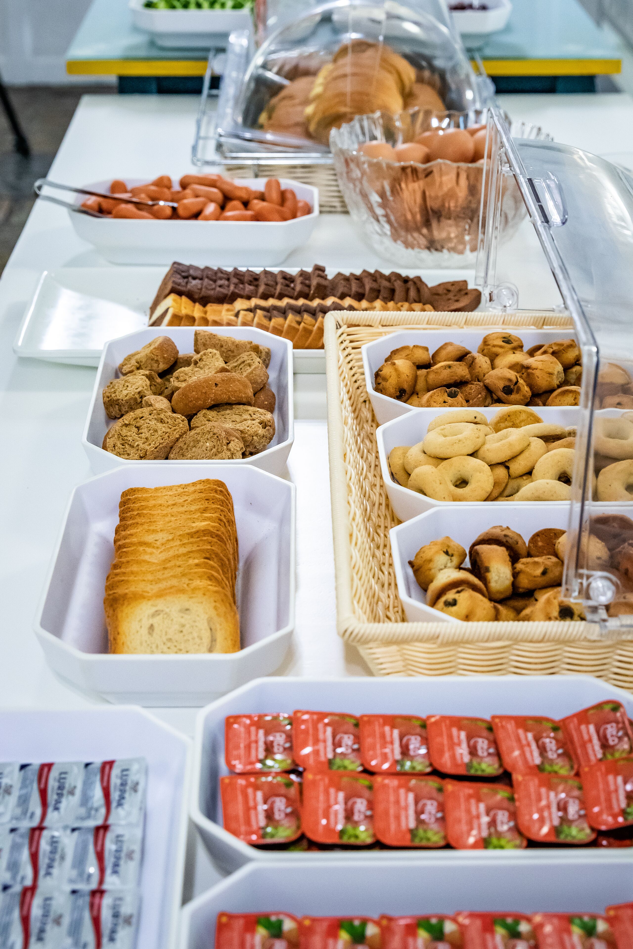 Un bufé con diversas opciones de comida, entre ellas bollería, galletas y sándwiches.