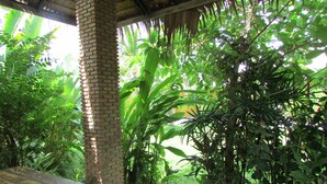An outdoor seating area with a brick pillar, surrounded by lush greenery and a thatched roof. - The Park Drive-Thru Check-In Resort (Thanyaburi)