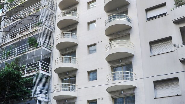 Un hotel de varios pisos con un patio central, balcones en cada planta y un diseño arquitectónico moderno.