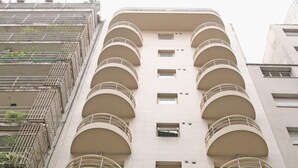 Un edificio de varios pisos con balcones, cada uno con barandilla de metal y una ventana pequeña.