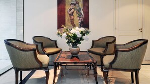 Una habitación con una mesa de centro de madera, dos sillones tapizados y un florero con flores.
