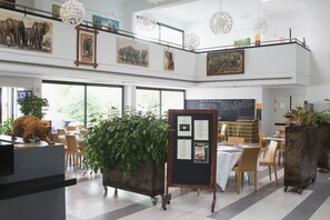 A spacious restaurant with high ceilings, large windows, and artwork on the walls. - MINA HOTEL LIBREVILLE (Libreville)