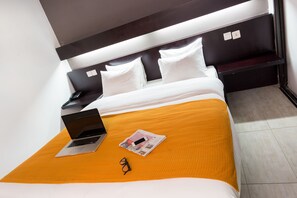 A neatly made bed with a laptop, glasses, and a magazine on an orange bedspread. - MINA HOTEL LIBREVILLE (Libreville)