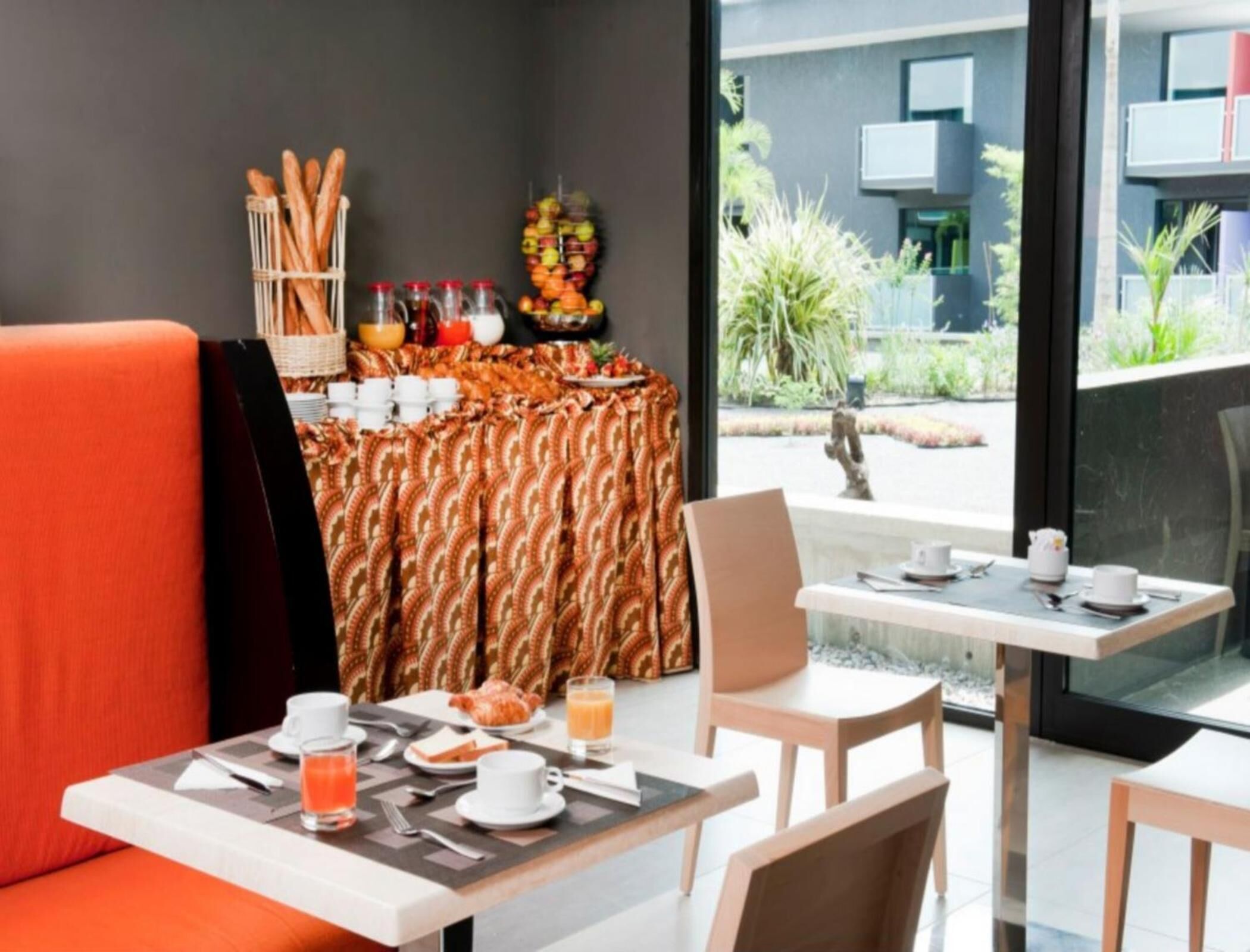 A breakfast setup with a table, chairs, and a buffet table with food and drinks.