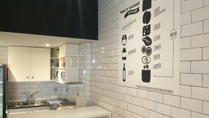A modern kitchen with white tiles, a white countertop, and a wall-mounted menu. - Chameleon Hostel (Alicante)