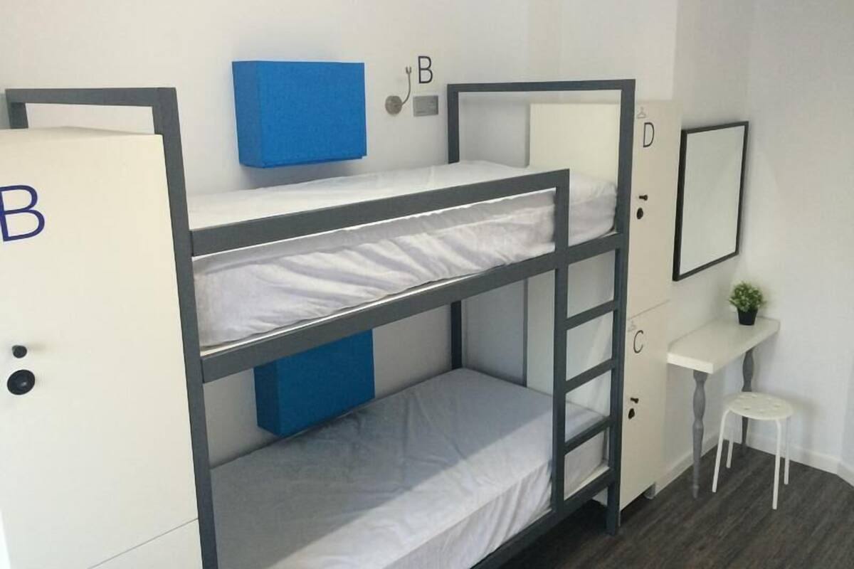A bunk bed room with a desk and a small stool.