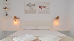 Un dormitorio minimalista con una cama grande, dos mesitas de noche e iluminación empotrada en la pared.