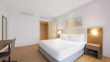 Una habitación de hotel con una cama grande, mesitas de noche, un escritorio y una silla.