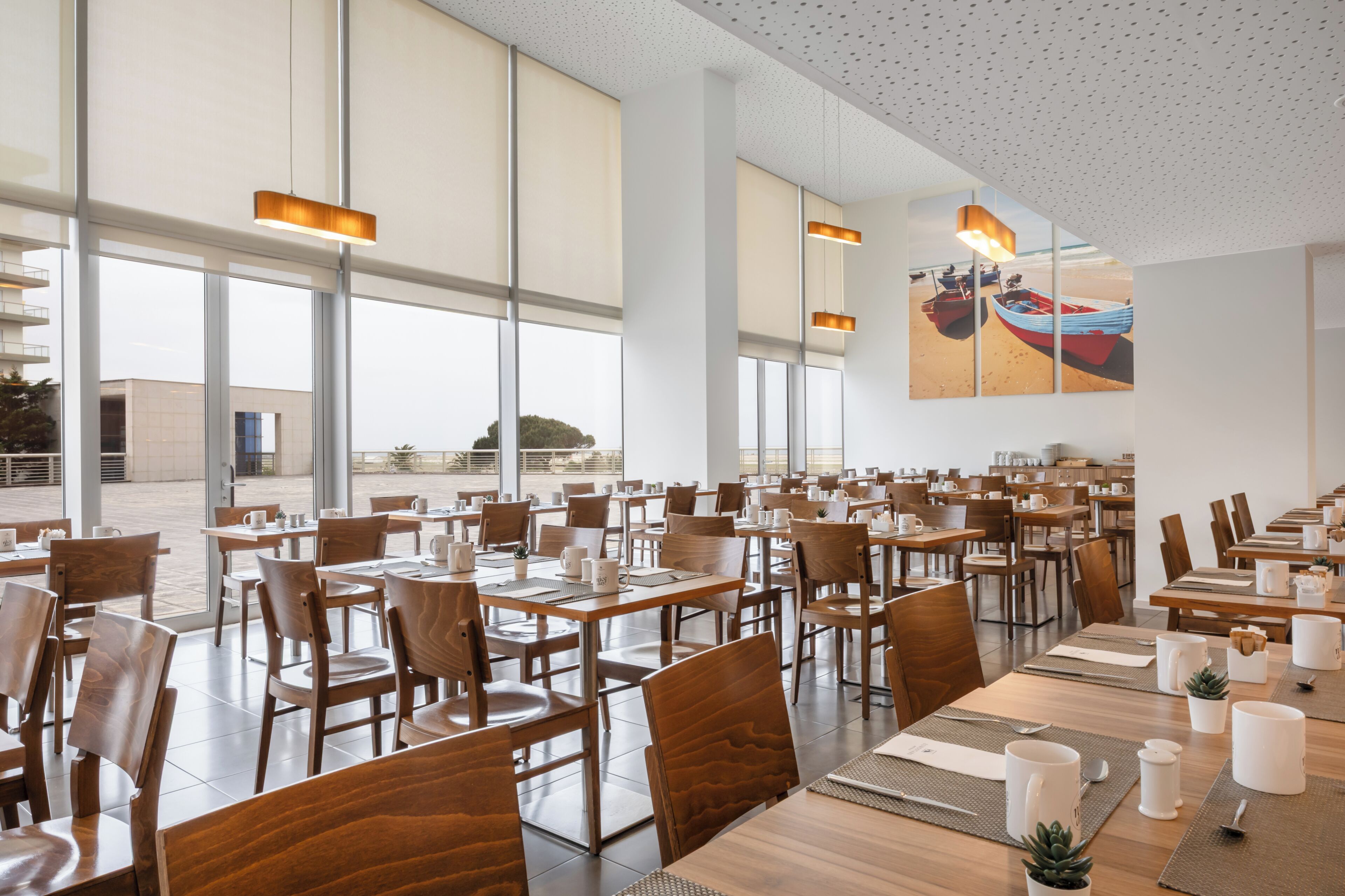 A spacious dining area with high ceilings, large windows, and wooden tables and chairs.