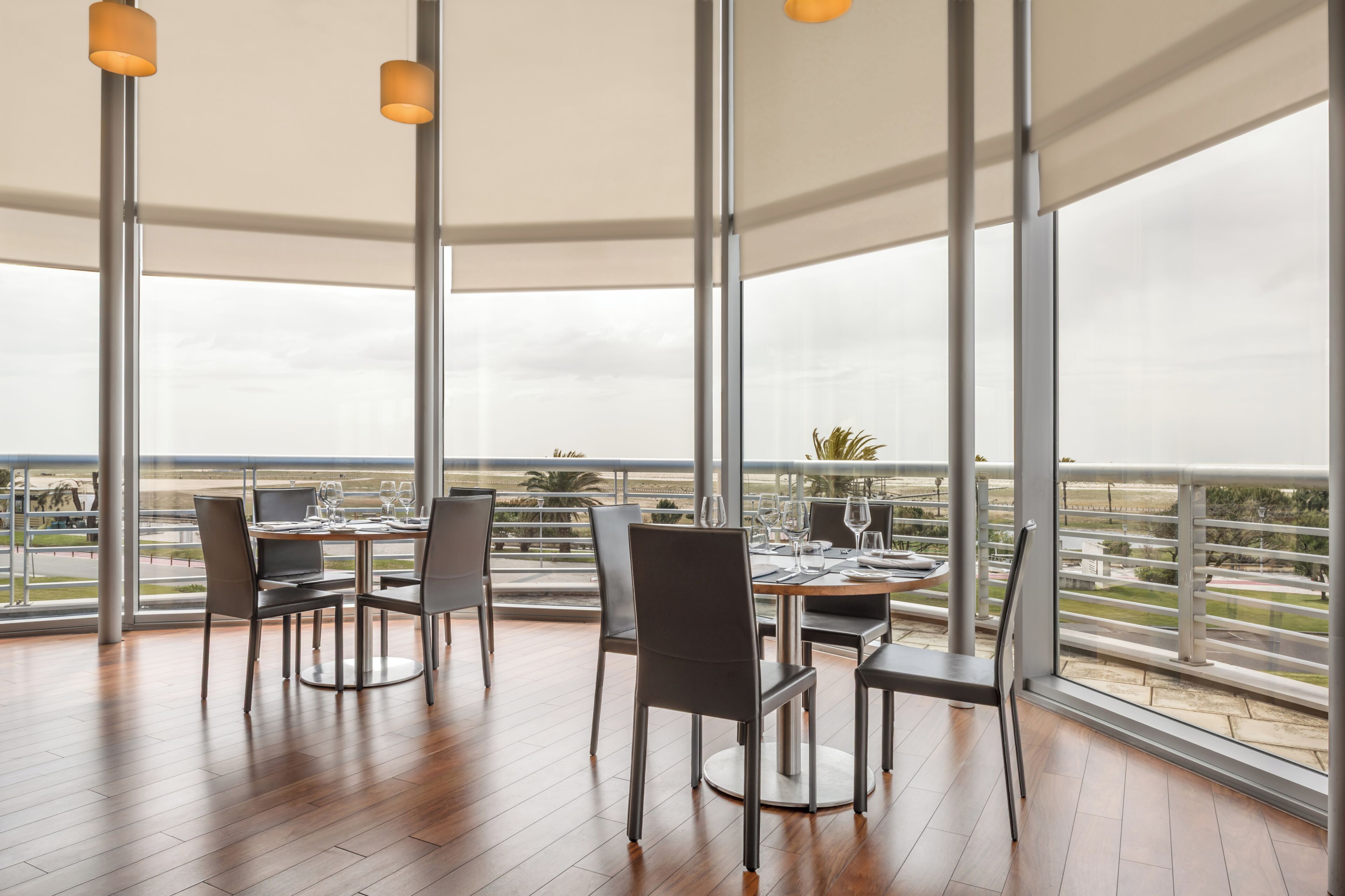 A dining area with a table set for four, large windows, and a view of the landscape.