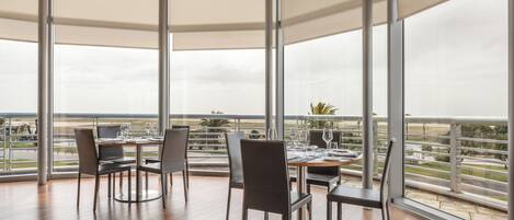 A dining area with a table set for four, large windows, and a view of the landscape.