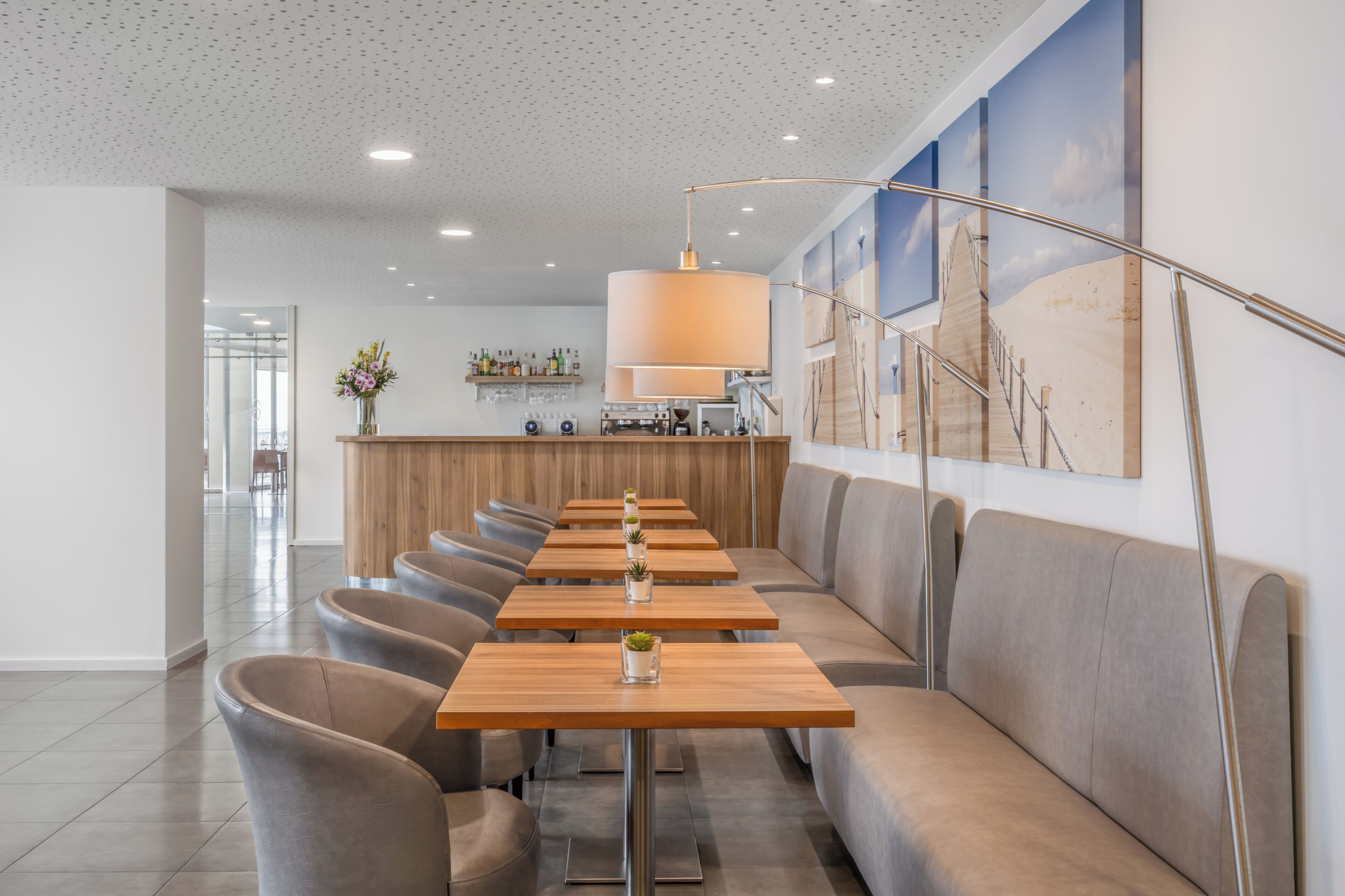 A modern restaurant with a long counter, cushioned seating, and a decorative wall.