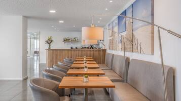 Een modern restaurant met een lange toonbank, zachte zitplaatsen en een decoratieve wand.