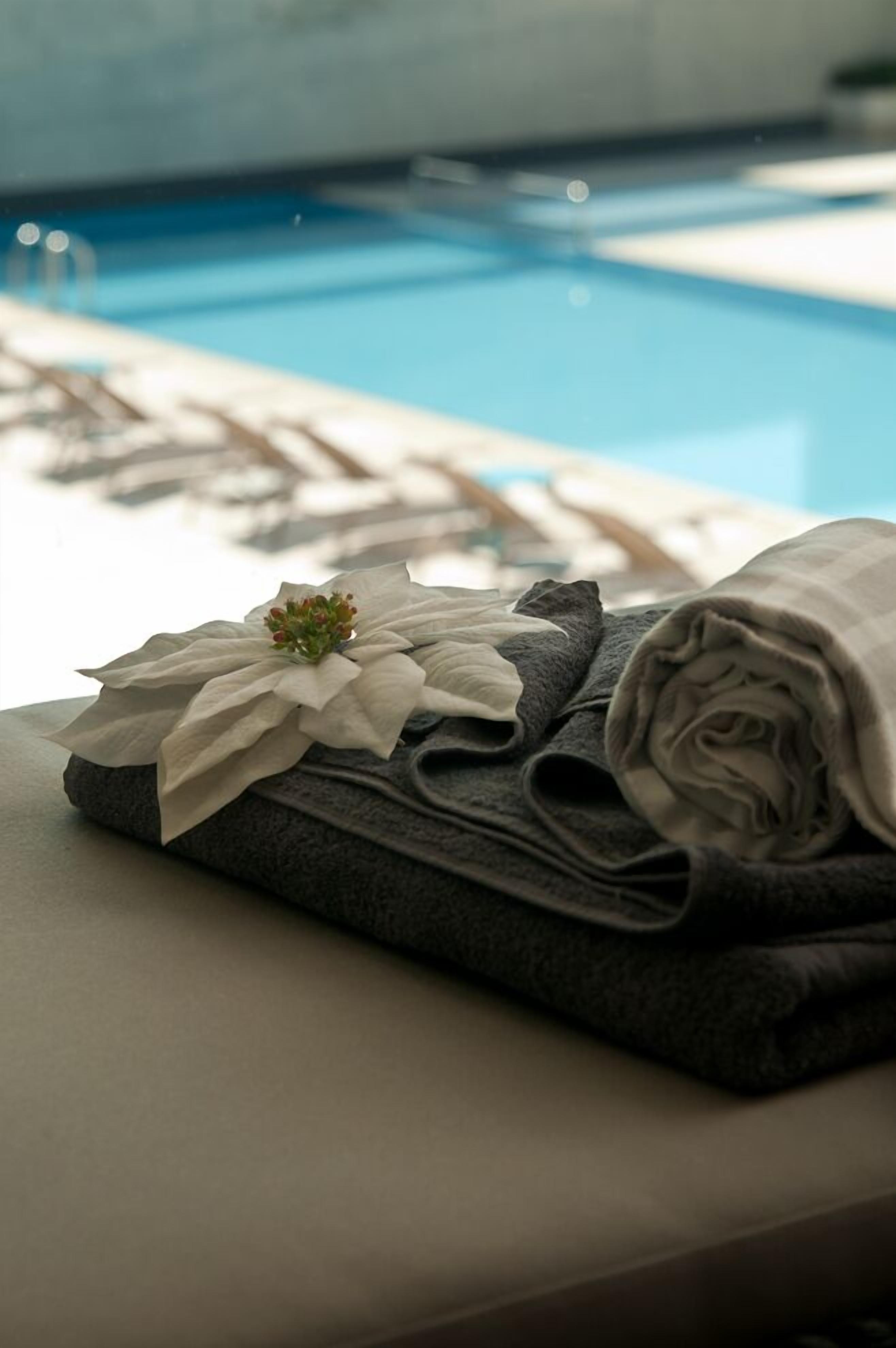 Una toalla doblada con una flor decorativa en una zona junto a la piscina.
